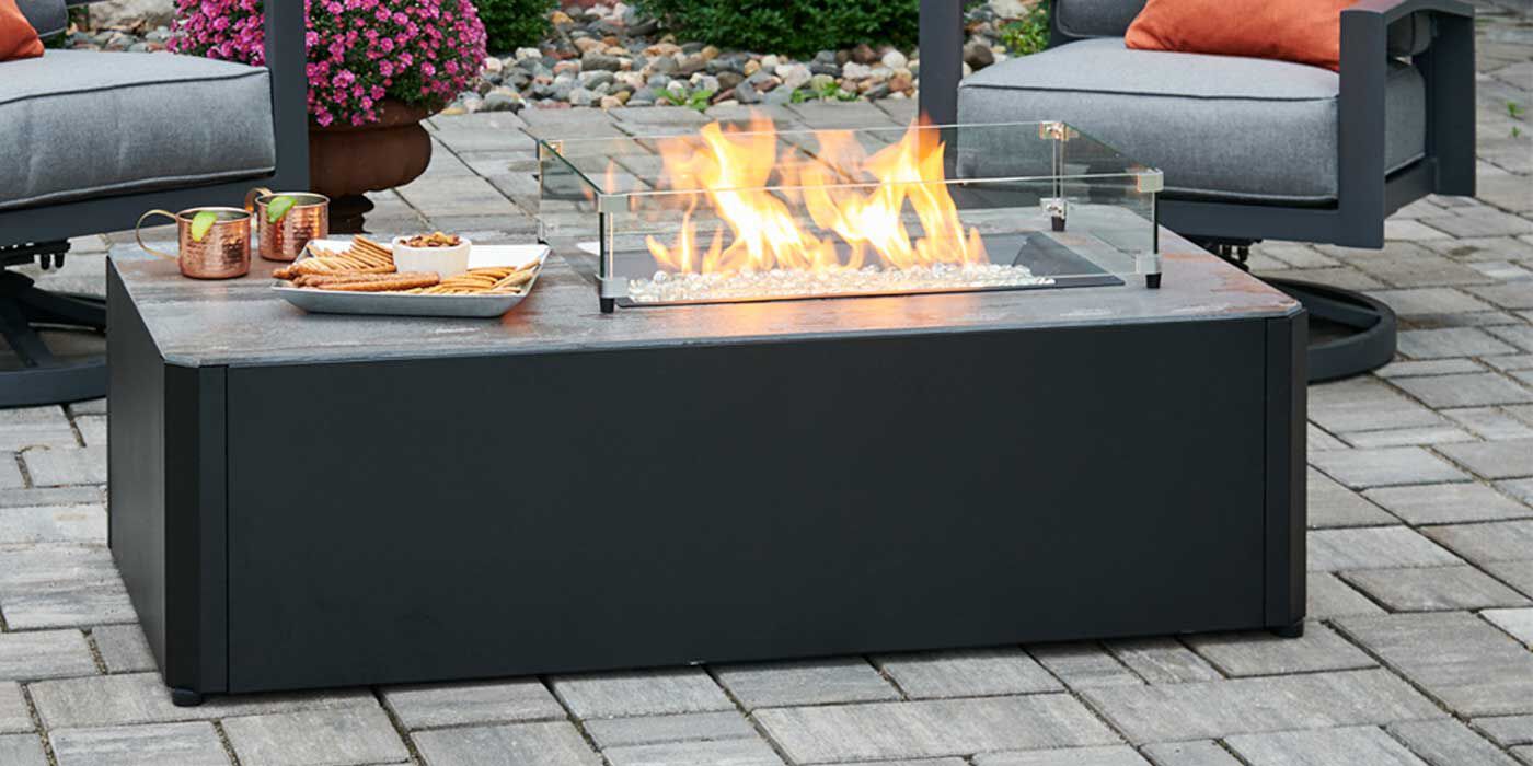 The Kinney Rectangular Gas Fire Pit Table by The Outdoor GreatRoom features a hidden tank design with a hollow base that holds your Propane tank.