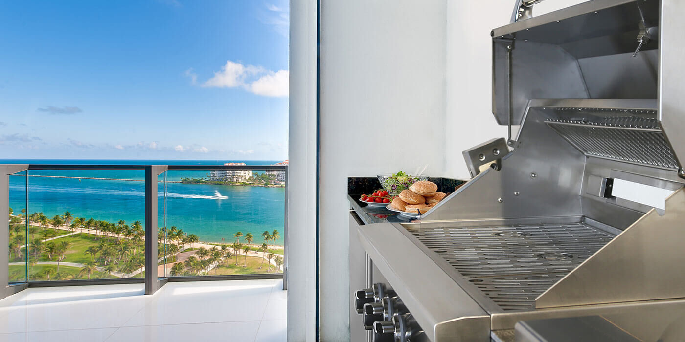 A stainless steel Summerset grill on a coastal balcony overlooking the ocean.