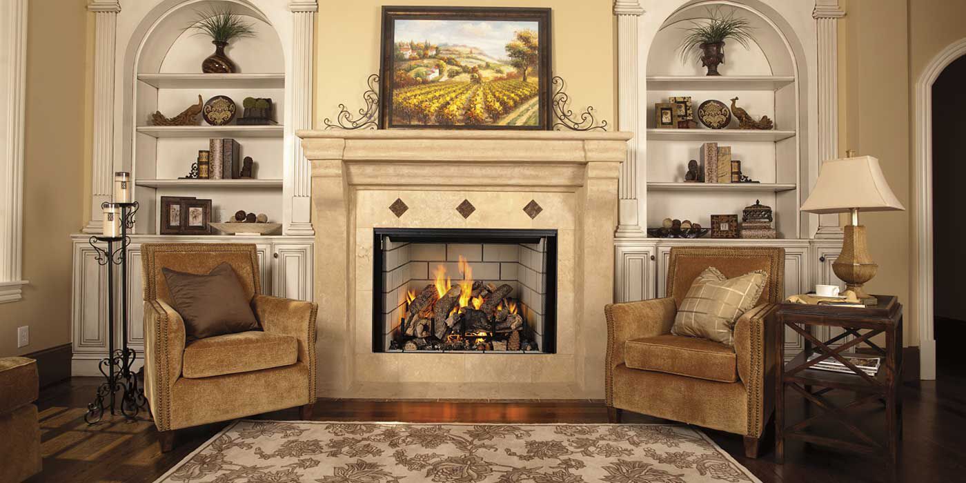 A traditional living room with two beige armchairs next to a decorative, white hearth and mantel with a square gas fireplace insert and rustic gas log set.