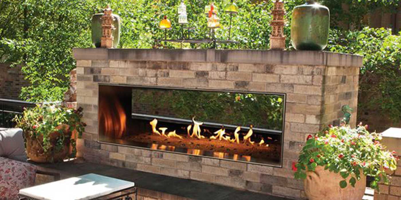 The Carol Rose 60" Linear See-Through Natural Gas Fireplace by Empire installed on an outdoor patio.