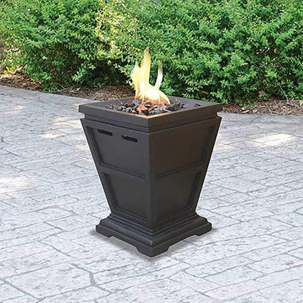 A small black fire column sitting on top of a brick patio.