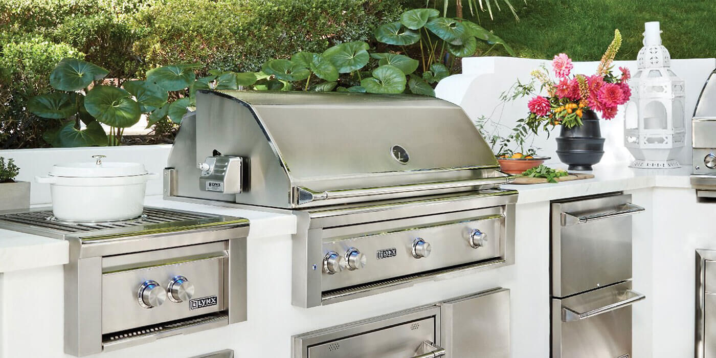 A custom outdoor kitchen island white stainless steel storage components and a matching Natural Gas stainless steel grill head.