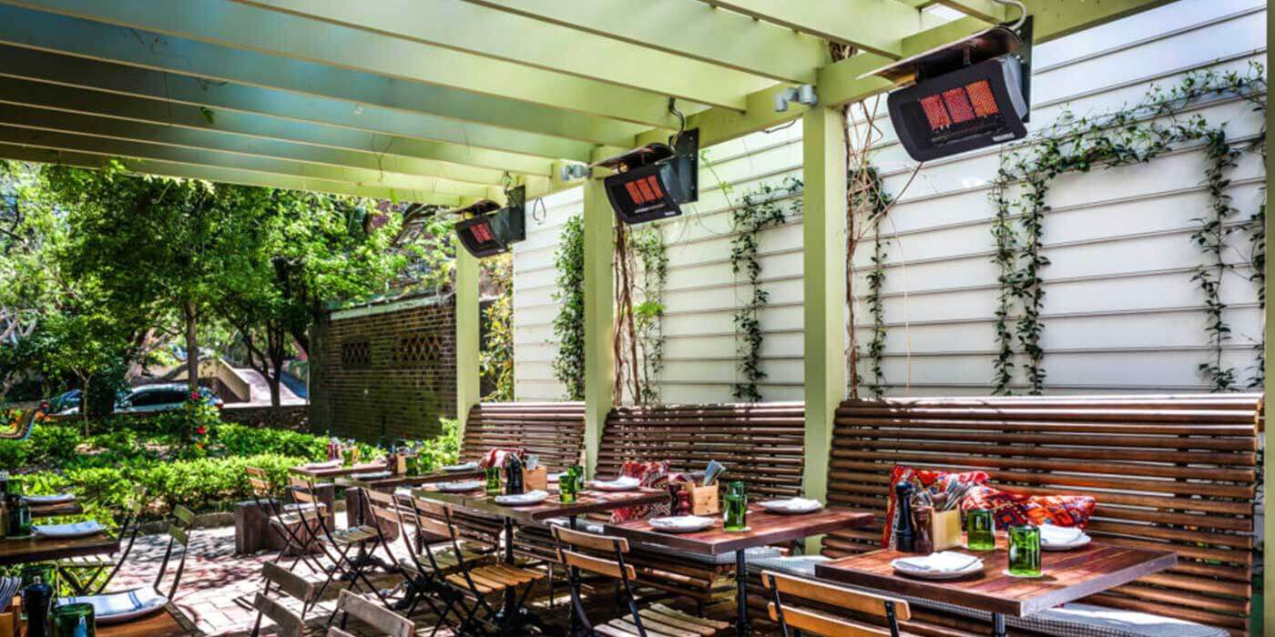 Three Bromic 500 Series gas patio heaters installed above booths and tables in an outdoor dining space.
