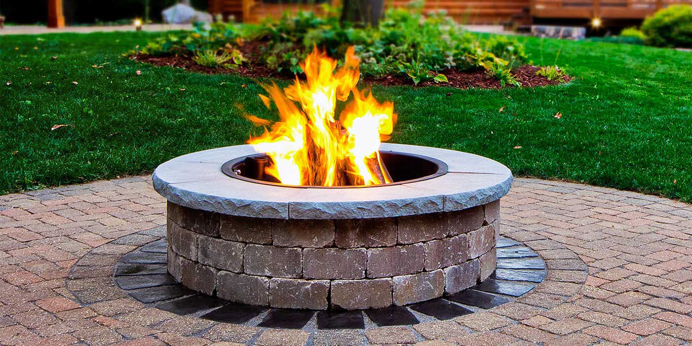 A large, custom-built fire pit made with brick pavers and a concrete top.