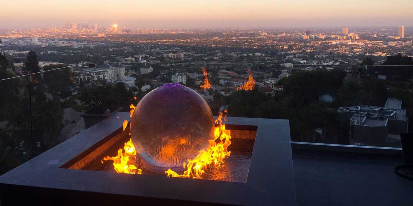 A rooftop view of Los Angeles with a large fountain and contemporary metal fire ball in the center.