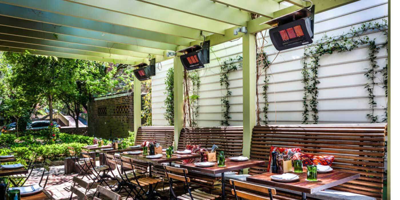 Bromic Natural Gas patio heaters installed above several outdoor booths and dining tables.