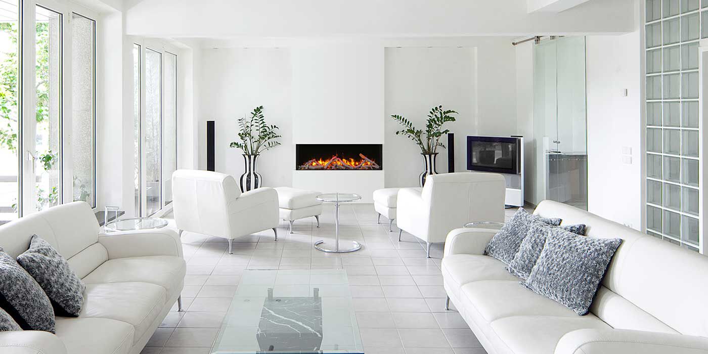 A minimalist living room with white floor and walls, a floor-to-ceiling window, white couches and accent chairs, and a linear electric fireplace.